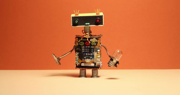 Comical robot handyman walks and shaking his arms. Toy cyborg with light bulb screwdriver. Orange wall yellow floor background