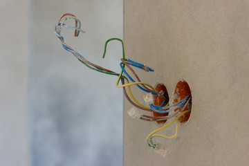 Electric socket with colorful wires in new house interior under construction
