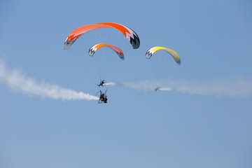 Paratroopers - multicolored powered parachutes during aircraft exhibition with trail of italian flag colors over Grado beach, Italy.