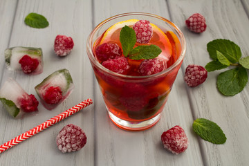 Homemade lemonade with raspberries and  lemon on the  wooden grey background