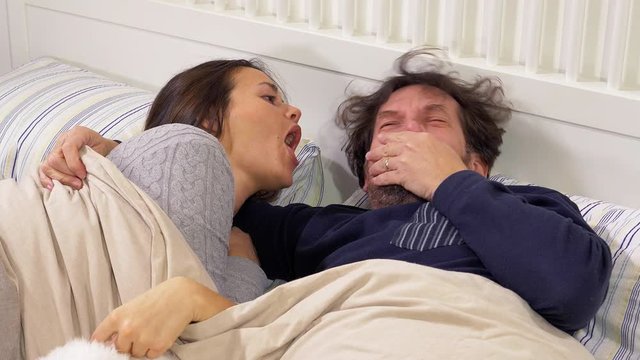 Funny couple playing in bed in the morning with bad breath