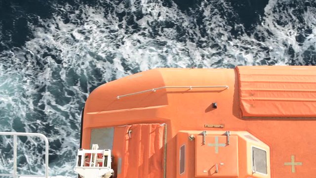 Passing Through Sea Water Under Orange Cruise Ship Lifeboat Closeup Video