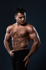 Fototapeta na wymiar Muscular bodybuilder on black background.Strong athletic man shows body,abdominal muscles,chest muscles,biceps and triceps.Work out,gaining weight. Bodybuilding concept.