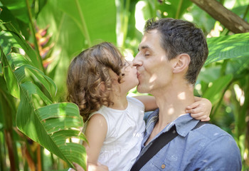 Portrait of a cheerful child kissing her father