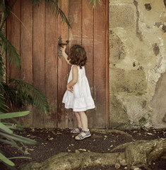 Little girl checking old, wooden door