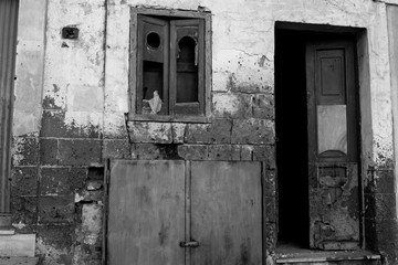 Ruined and Broken Facade With an Open  Door and a Window With a Broken Glass