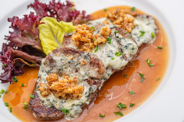 grilled beef slices with cheese and walnuts and sauce on white plate