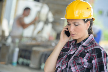 beautiful builder helmet talking by phone at construction site