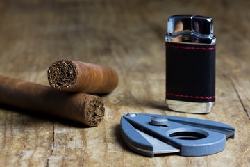 Two Cuban cigars with a lighter and a cutter