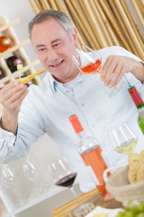 handsome mature man tasting glass of rose wine