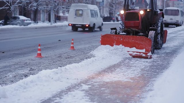 Tractor cleaning snow snowthrower. Removing snow with plow. Close up of iron snowplow pushing a lot of snow away.