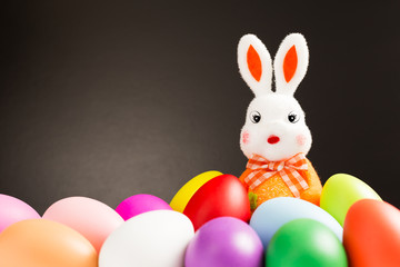Easter bunny and colorful decorative eggs on black background with copy space, Easter holidays concept
