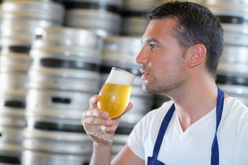 handsome brewer in uniform tasting beer at the brewery