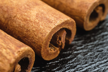 Cinnamon stick on black leather texture background, macro image