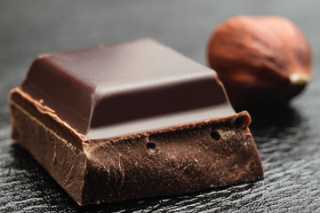 Dark, bitter chocolate in cubes shape on black leather texture background