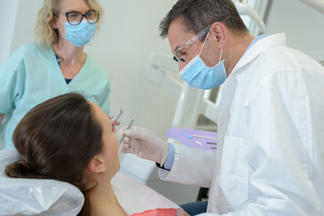 male dentist his assistant and female patient in dental office