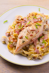 Chicken breast and egg noodles with bacon and mushrooms in creamy sauce. vertical
