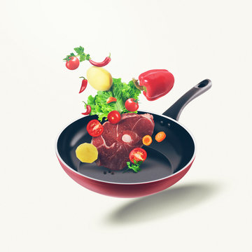 Flying organic food and fresh meat on frying pan. Food illustration different vegetables and fresh meat on isolated white background