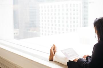 woman working on laptop against bright window with copy space