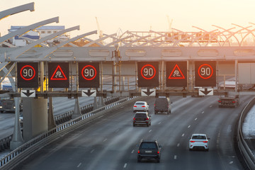 High-speed highway with traffic cars and speed limit signs and a slippery road warning.