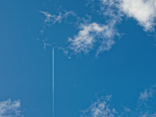 airplane flies between bright white clouds and blue sky