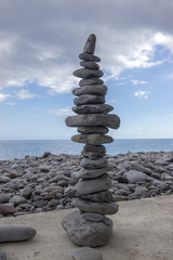 Fototapeta na wymiar High stone cairn tower, poise stones, rock zen sculpture, light grey pebbles