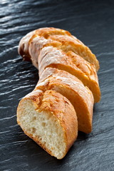 Fresh baguette bread vertical close up shot on the dark background