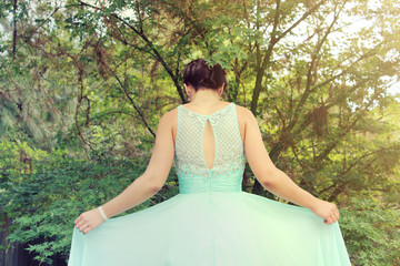 Portrait of the back of a young woman posing and wearing her formal dress in a park, dressed for her school formal © Milanna