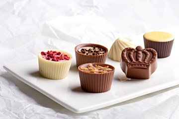 Chocolate pralines assortment on a white background. Selection of finest white, milk and dark chocolate.
