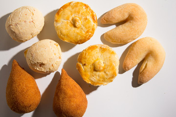 Assorted snacks: Pao de Queijo, Chipa, Coxinha and Empada. Group of typical food from Brazil. Top View, flat lay design on white background.