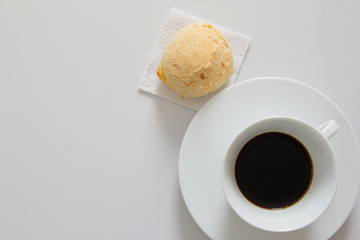 Pao de Queijo is a cheese bread ball from Brazil. Also known as Chipa, Pandebono and Pan de Yuca. Snack and espresso cup on white background, minimalism.