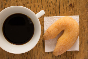Cheese bread known as Chipa in Brazil, shaped like a horseshoe. Snack and espresso coffee on rustic wood, flat design.