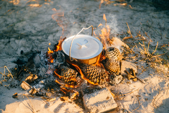 Boiling water in metal pot outdoors. Tea preparation in wild nature in camping trip. Tourist equipment. Cooking in travel on bonfire with firewoods. Adventure in Portugal. Food and drinks in morning.