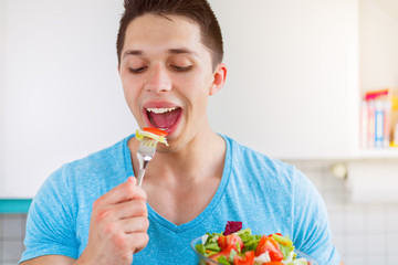 Junger Mann isst essen Salat in der Küche gesunde Ernährung vegan