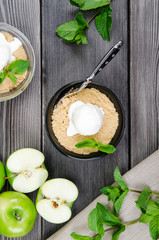 Top view close up Apple crumble dessert with vanilla ice cream, green mint on grey wooden table. fork with cake on tablecloth