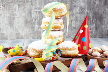 German donuts with jam and icing sugar. Carnival powdered sugar raised donuts with paper streamers.