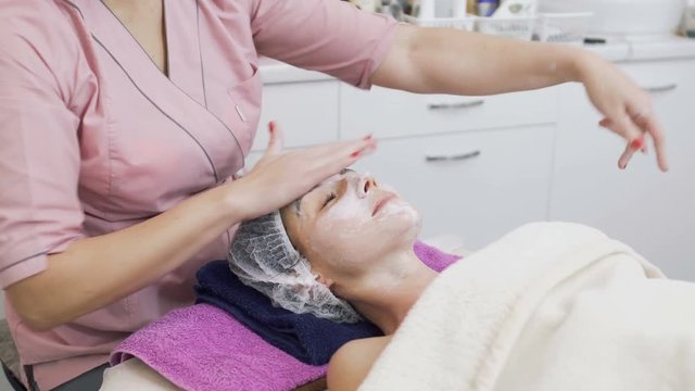 Young woman enjoys procedure of facial massage