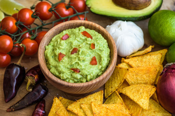 Guacamole in Wooden Bowl with Tortilla Chips and Ingredients