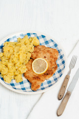 Traditional German or Austrian Wiener Schnitzel or Schnitzel Wiener Art, breaded and pan-fried butterfly cutlet of pork, veal of chicken meat served with slice of lemon and homemade potato salad