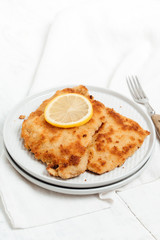 Traditional German or Austrian Wiener Schnitzel or Schnitzel Wiener Art made of breaded and pan-fried butterfly cutlet of pork, veal of chicken meat served with a slice of lemon