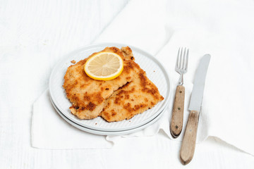 Traditional German or Austrian Wiener Schnitzel or Schnitzel Wiener Art made of breaded and pan-fried butterfly cutlet of pork, veal of chicken meat served with a slice of lemon