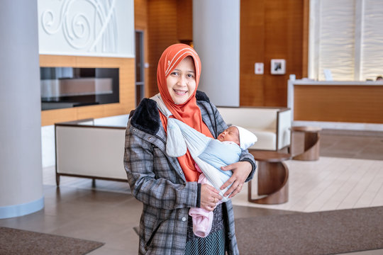 A mother from Indonesia with her newborn baby pose in and around their apartment in Toronto