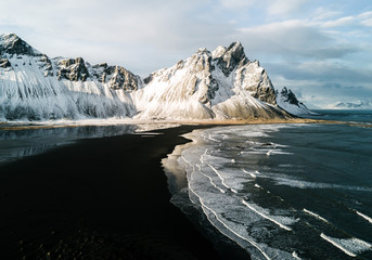 View of black sand beach with snow covered mountain in background