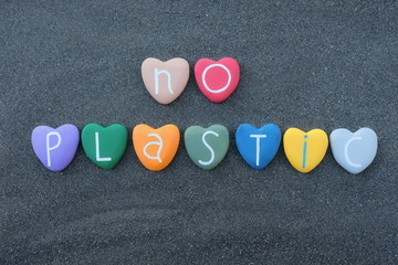 No plastic text with multicolored heart stones over black volcanic sand