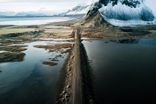 Aerial of Stokksnes beach with long road in Iceland during winter and sunset with mountain in background