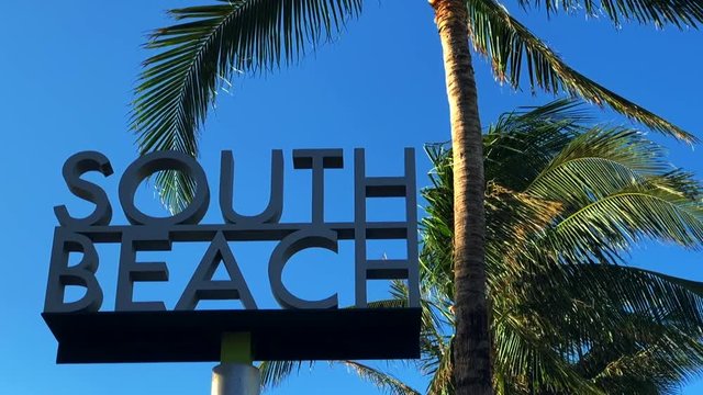 South Beach sign against palm trees in bright blue sky in Miami, Florida 