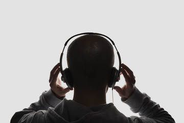 Male silhouette with hands holding headphones
