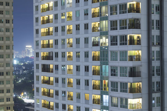 Residential Apartment Windows At Night For Electrical And Power Energy Concept.  Individual Living Spaces And Urban Sprawl To Highrise Buildings.