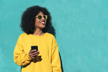 Beautiful afro american woman using mobile in the street.
