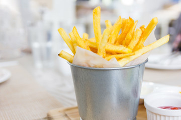 French Fries, Wrapped with a paper in a Stainless small bucket on a wooden table, Selective focus